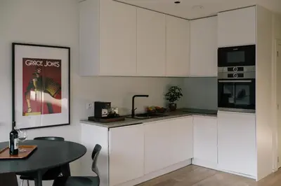 a kitchen with white cabinets and a black table and a table and a tablektop at A Place Antwerp - Boutique Suites & Flats - Vrijdagmarkt 18 in Antwerp