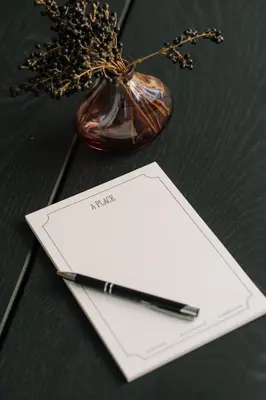 a pen and a notebook on a table with a vase at A Place Antwerp - Boutique Suites & Flats - Leeuwenstraat 15 in Antwerp