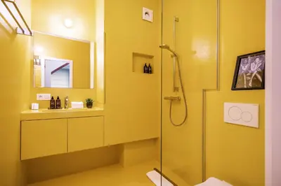a yellow bathroom with a shower and a sink at A Place Antwerp - Boutique Suites & Flats - Leeuwenstraat 15 in Antwerp