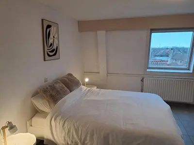 a bedroom with a large white bed and a window at De Peperbus in Lokeren