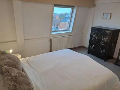 a bedroom with a large white bed and a window at De Peperbus in Lokeren