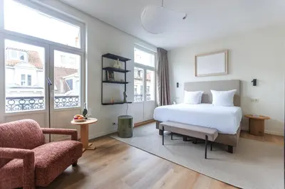 a bedroom with a white bed and a chair at Le Catherine by Sweett in Brussels