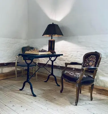 two chairs and a table with a lamp and a chessboard at The Mystical Suite in Antwerp