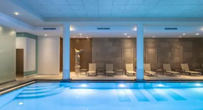 a swimming pool in a building with chairs and a statue at Sunset Paradise Tomorrowland hotel and transport at Hyllit Antwerp in Antwerp