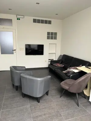 a living room with a black couch and chairs at Kamer Demer in Aarschot