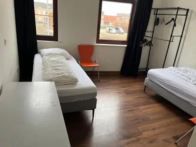 a room with two beds and a table and two windows at Kamer Demer in Aarschot