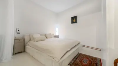 a white bedroom with a white bed and a table at Cosy loft near City Centre, Terra CasaMia in Antwerp
