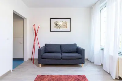 a blue couch in a living room with a window at Apartment over two floors for 5 guests near Midi & Grand Place in Brussels