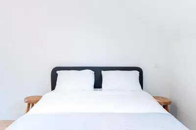 a bed with white sheets and pillows against a white wall at Apartment over two floors for 5 guests near Midi & Grand Place in Brussels