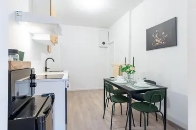 a small kitchen with a black table and green chairs at Apartment over two floors for 5 guests near Midi & Grand Place in Brussels