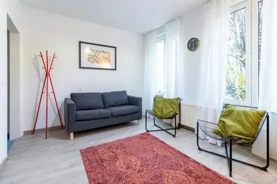 a living room with a blue couch and two chairs at Apartment over two floors for 5 guests near Midi & Grand Place in Brussels