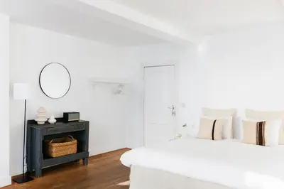a white bedroom with two beds and a mirror at The Collector's House in Antwerp