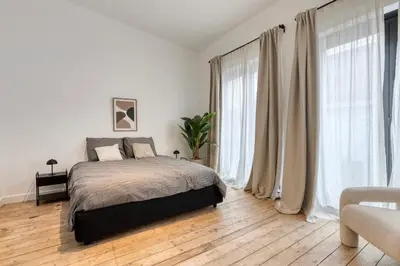 a white bedroom with a bed and large windows at Spacious 3-bedroom apartment with terrace Zurenborg in Antwerp