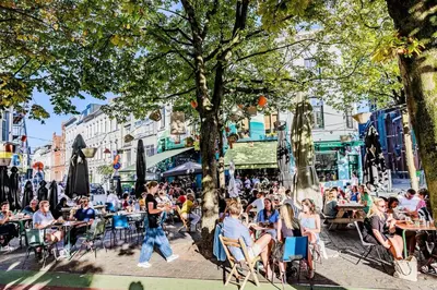 a group of people sitting at tables in a street at Spacious 3-bedroom apartment with terrace Zurenborg in Antwerp