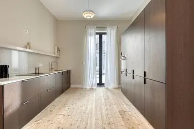 a kitchen with wooden cabinets and a large window at Spacious 3-bedroom apartment with terrace Zurenborg in Antwerp