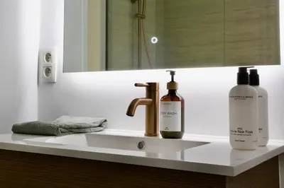 a bathroom sink with two bottles of soap and a mirror at Hip apartment between South & Historic Antwerp in Antwerp
