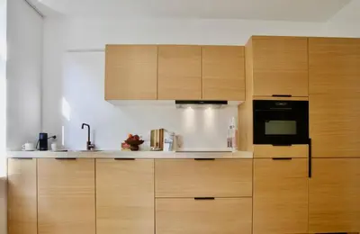 a kitchen with wooden cabinets and a black microwave at Hip apartment between South & Historic Antwerp in Antwerp