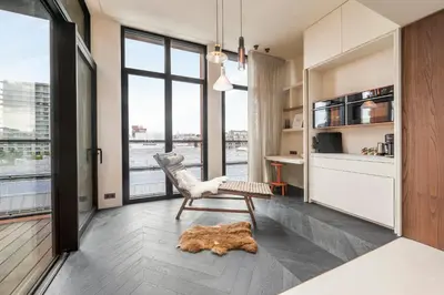 a living room with a chair and a desk and window at Montevideo Penthouse in Antwerp