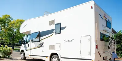 a white rv parked in a parking lot at Camper max 5p, unique experience, terras, central Belgium in Denderleeuw