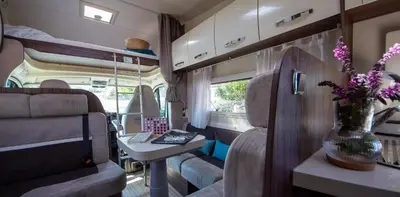 an interior view of an rv with a table and flowers at Camper max 5p, unique experience, terras, central Belgium in Denderleeuw