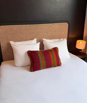 a bed with white pillows and a red and green pillow at Modern 2-Bedroom Apartment for 4 Guests, In a Prime Location Close to the Train Station and the Historic Center of Ghent in Ghent