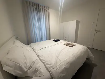 a bedroom with a white bed with a robe on it at Business Accommodation Mol Centre in Mol