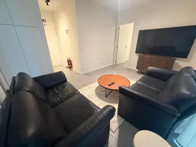 a living room with a black leather couch and a table at Business Accommodation Mol Centre in Mol