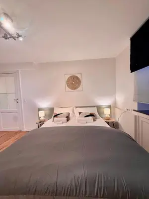 a large bed in a white room with two lamps at European Lodge Rooms Brussels in Brussels