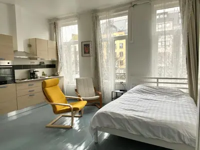 a bedroom with a bed and a chair and a kitchen at Mini Urban Stay in Brussels