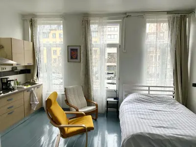 a bedroom with a bed and a chair and windows at Mini Urban Stay in Brussels