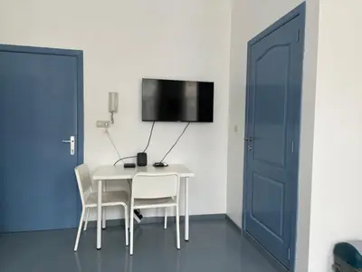 a room with a table and chairs and a tv on a wall at Mini Urban Stay in Brussels