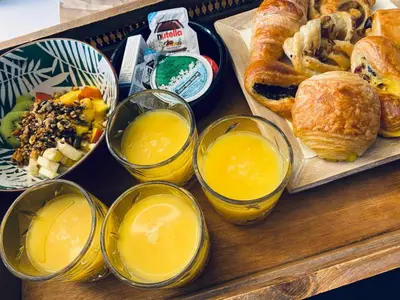 a tray with various types of bread and orange juice at Casa Cava B&B in Dendermonde