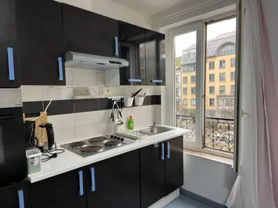 a kitchen with black cabinets and a sink and a window at Tiny Central Stay in Brussels