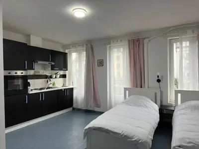 a bedroom with a bed and a kitchen with windows at Tiny Central Stay in Brussels