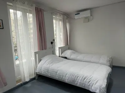 two beds in a room with two windows at Tiny Central Stay in Brussels