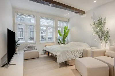 a bedroom with a bed and a couch and windows at Cozy Stay in the Heart of Mechelen in Mechelen