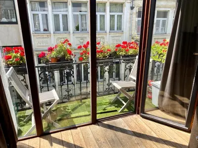 an open window with two chairs and flowers on a balcony at Great apartment with a soul in the middle of the center in Ghent
