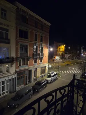 two cars parked in front of a building at night at Pb155, balcony with street view in Brussels