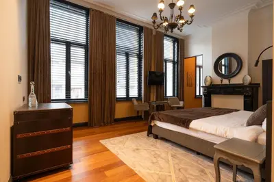 a bedroom with a bed and a desk and windows at Civiltà Boutique in Antwerp