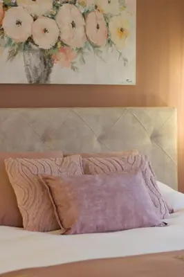 a bed with a pillow and a painting of flowers at Bed and Breakfast L'Orée Du Bois in Wavre