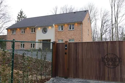 a house with a wooden gate and a fence at Bed and Breakfast L'Orée Du Bois in Wavre