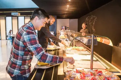 two men are preparing food at a buffet at Antwerp Central Youth Hostel in Antwerp