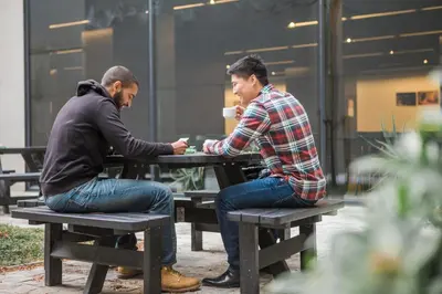 two men sitting at a picnic table talking at Antwerp Central Youth Hostel in Antwerp