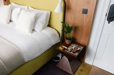 a hotel room with a bed and a night stand with a plant at A Place Antwerp - Boutique Suites & Flats - Schuttershofstraat 55 in Antwerp
