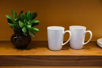 three white coffee mugs sitting on a table with a vase at A Place Antwerp - Boutique Suites & Flats - Schuttershofstraat 55 in Antwerp