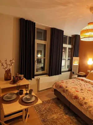 a bedroom with a bed and a table and windows at Cozy Renovated Studio in Central Brussels in Brussels