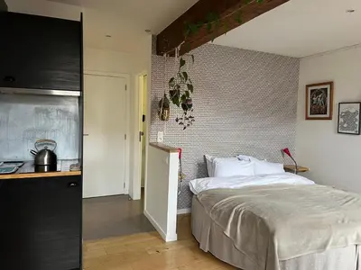 a bedroom with a large bed and a kitchen at Cozy studio-city center in Brussels