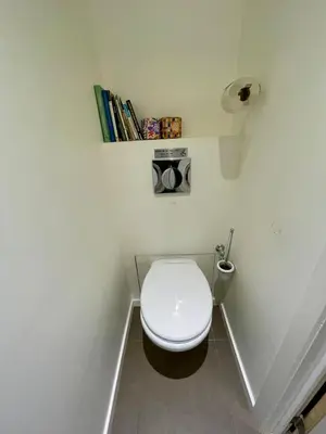 a small bathroom with a toilet with a book shelf at Cozy studio-city center in Brussels