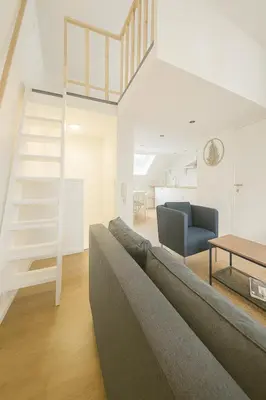 a living room with a gray couch and a ladder at Modern Loft 1BR Sofa Bed 10min to Center in Brussels