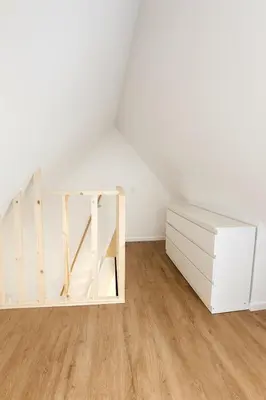 an attic room with a white dresser and a staircase at Modern Loft 1BR Sofa Bed 10min to Center in Brussels